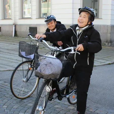 Två medarbetare med cyklar skrattar tillsammans på en gata