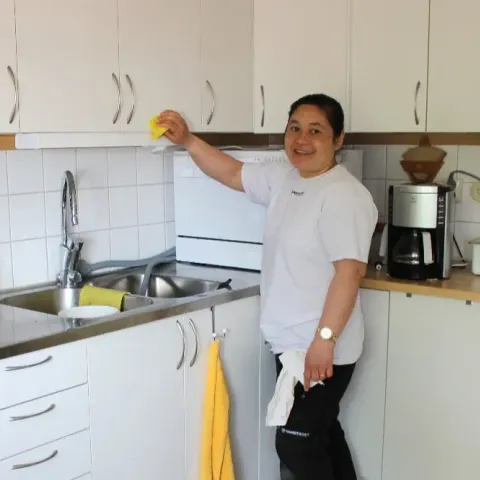 Medarbetare torkar av köksskåp hemma hos en kund